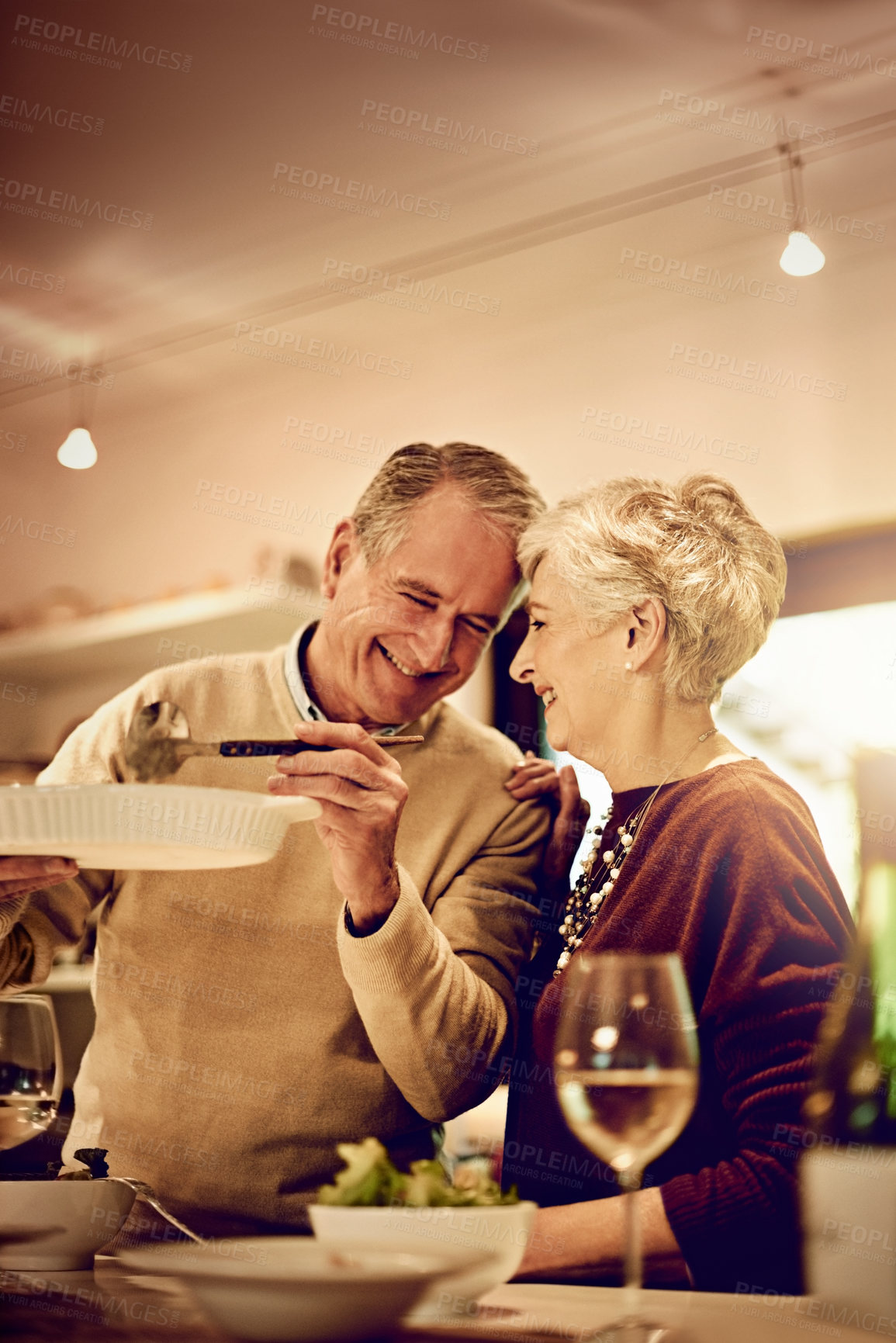 Buy stock photo Shot of an elderly couple dishing up a meal in their kitchen at home