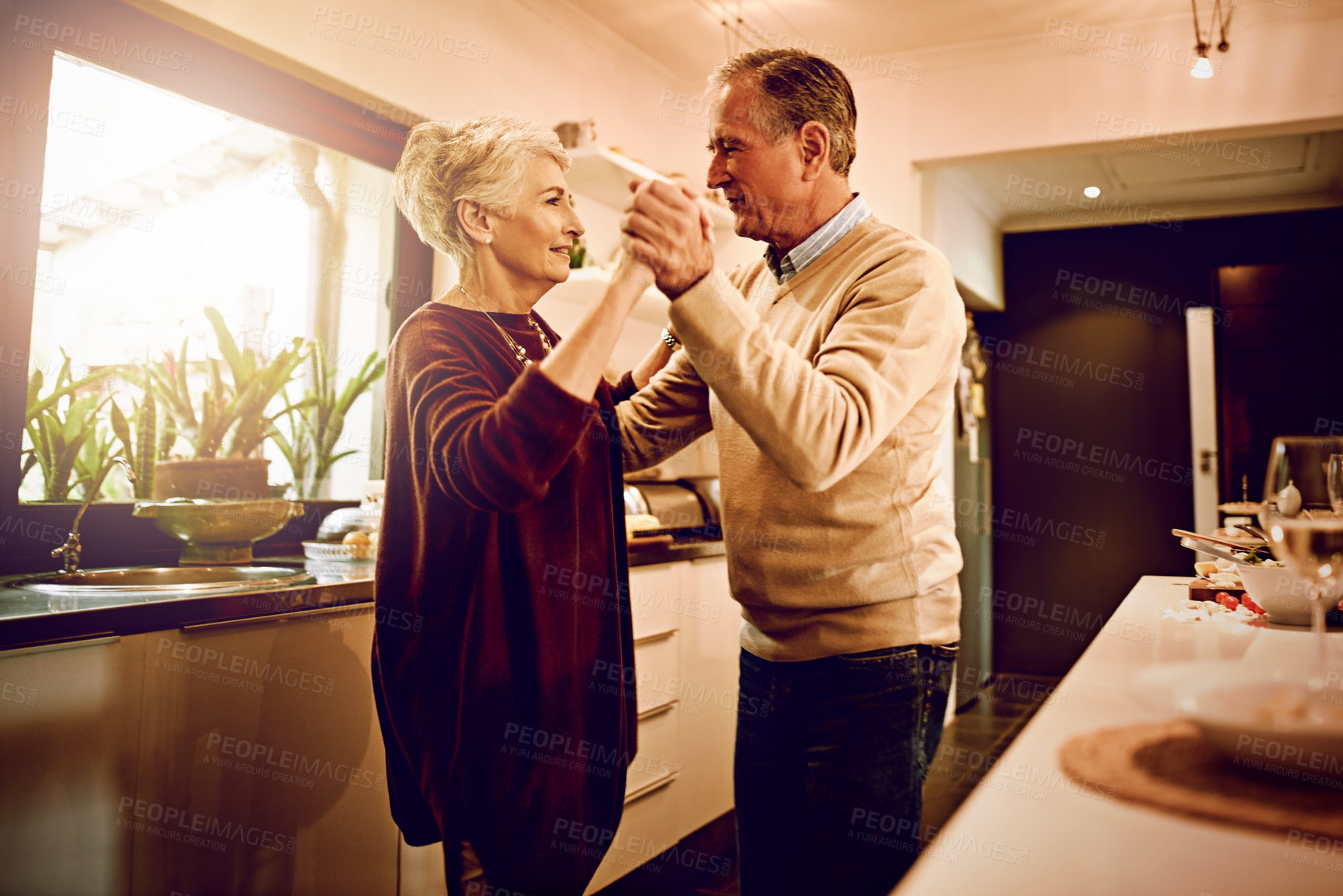Buy stock photo Shot of an elderly couple dancing with each other in their kitchen