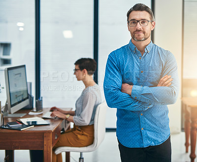 Buy stock photo Portrait of a mature businessman standing in an office with a colleague in the background