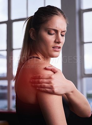 Buy stock photo Shot of a sporty young woman holding her injured shoulder that's highlighted in red