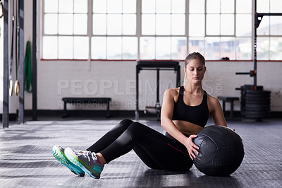 Buy stock photo Shot of a young woman using a medicine ball in an exercise routine