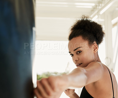 Buy stock photo Cropped shot of a sporty young woman working out with a punching bag outside