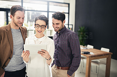 Buy stock photo Shot of a team of businesspeople discussing something on a digital tablet