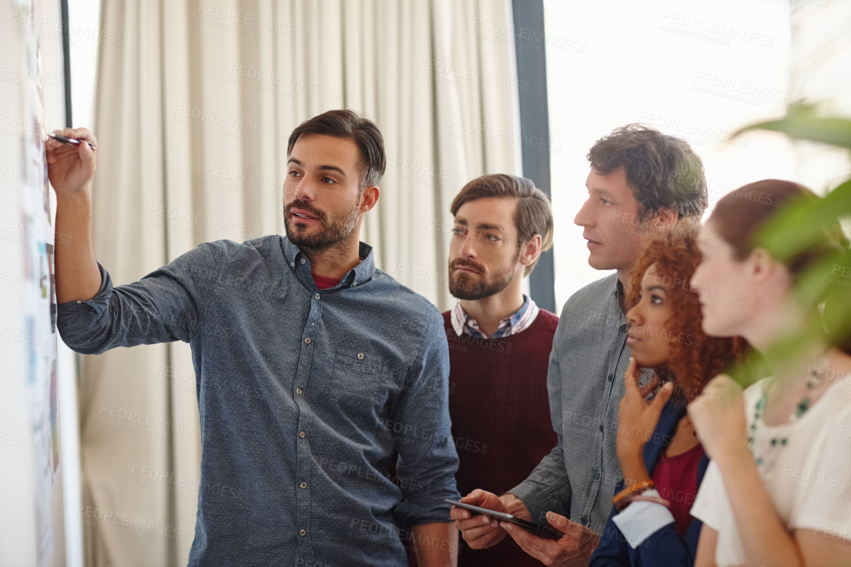 Buy stock photo Shot of a group of businesspeople listening to a colleague's presentation in the office