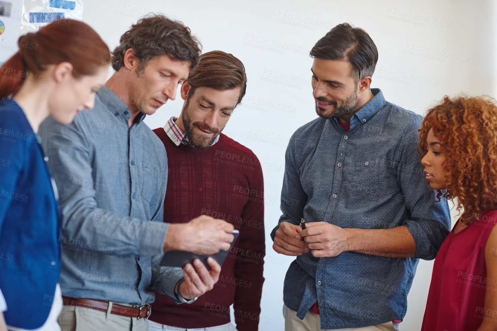 Buy stock photo Shot of a group of businesspeople looking at a tablet together in the office