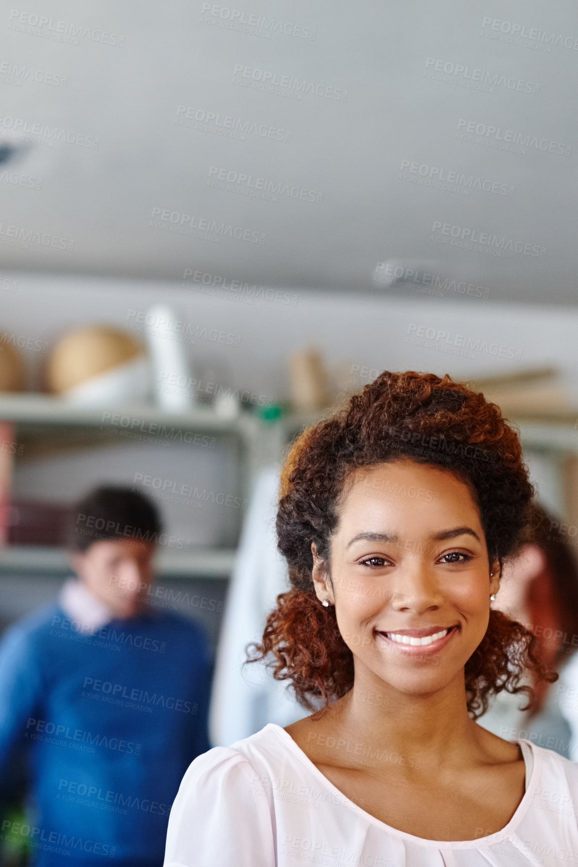 Buy stock photo Portrait of a young fashion designer standing in the workshop while her colleagues work in the background