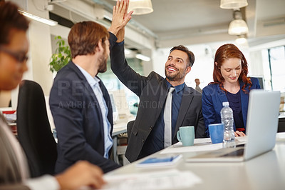 Buy stock photo Shot of colleagues giving each other a high five during a meeting at work
