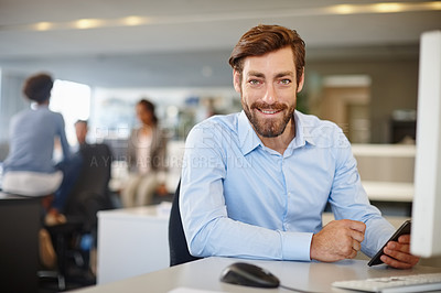Buy stock photo Portrait of a happy businessman using a computer and mobile phone at his work desk