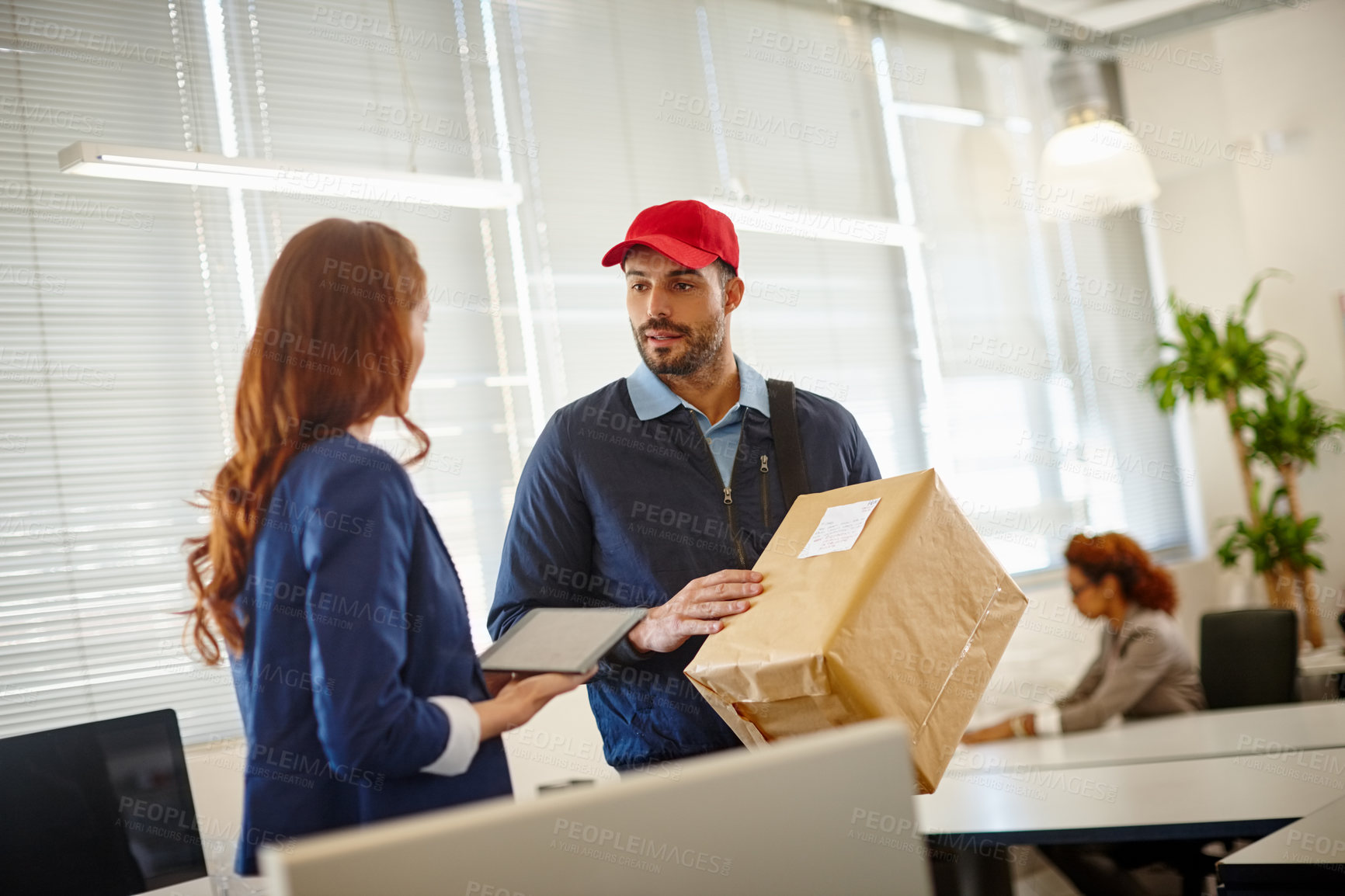 Buy stock photo Shot of a young woman receiving a package from a deliveryman at her office