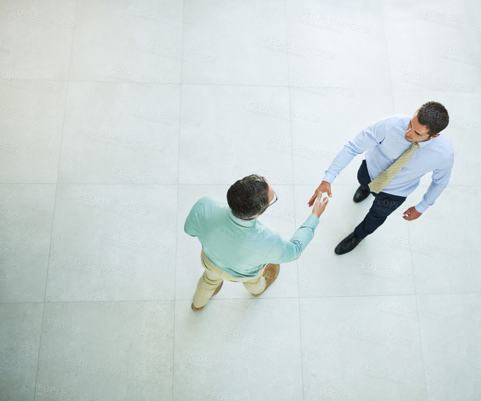 Buy stock photo High angle shot of two businessmen shaking hands in the office