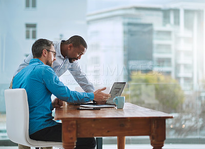 Buy stock photo Shot of two businessmen working on a laptop in their office