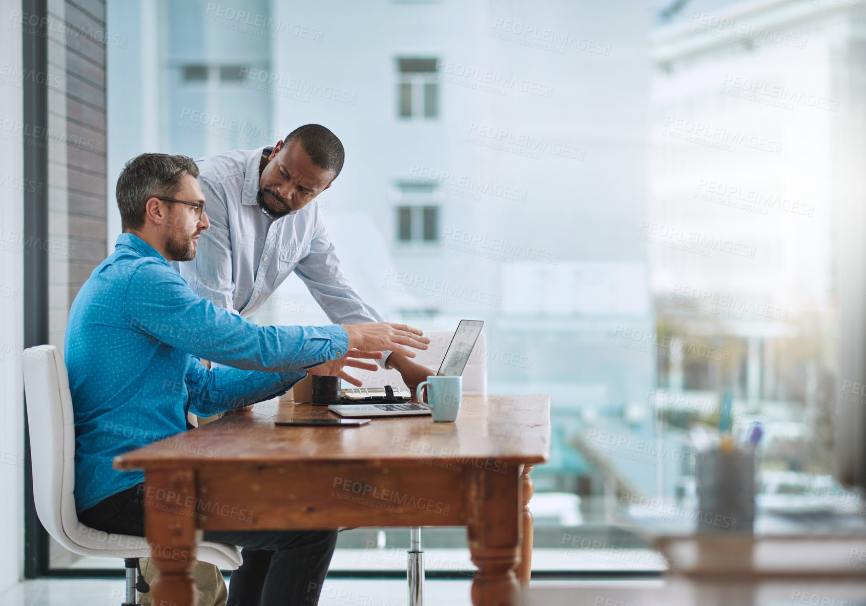 Buy stock photo Shot of two businessmen working on a laptop in their office