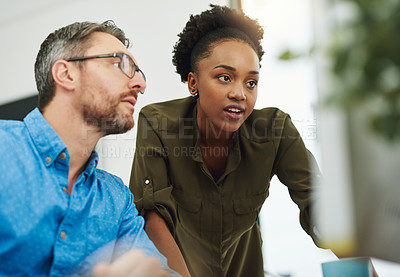 Buy stock photo Shot of two businesspeople working on a computer in their office