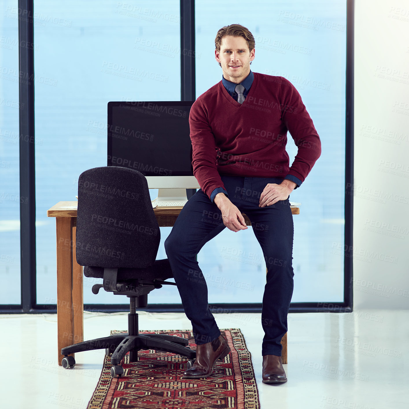 Buy stock photo Portrait of a young designer sitting on his work station desk in front of a window