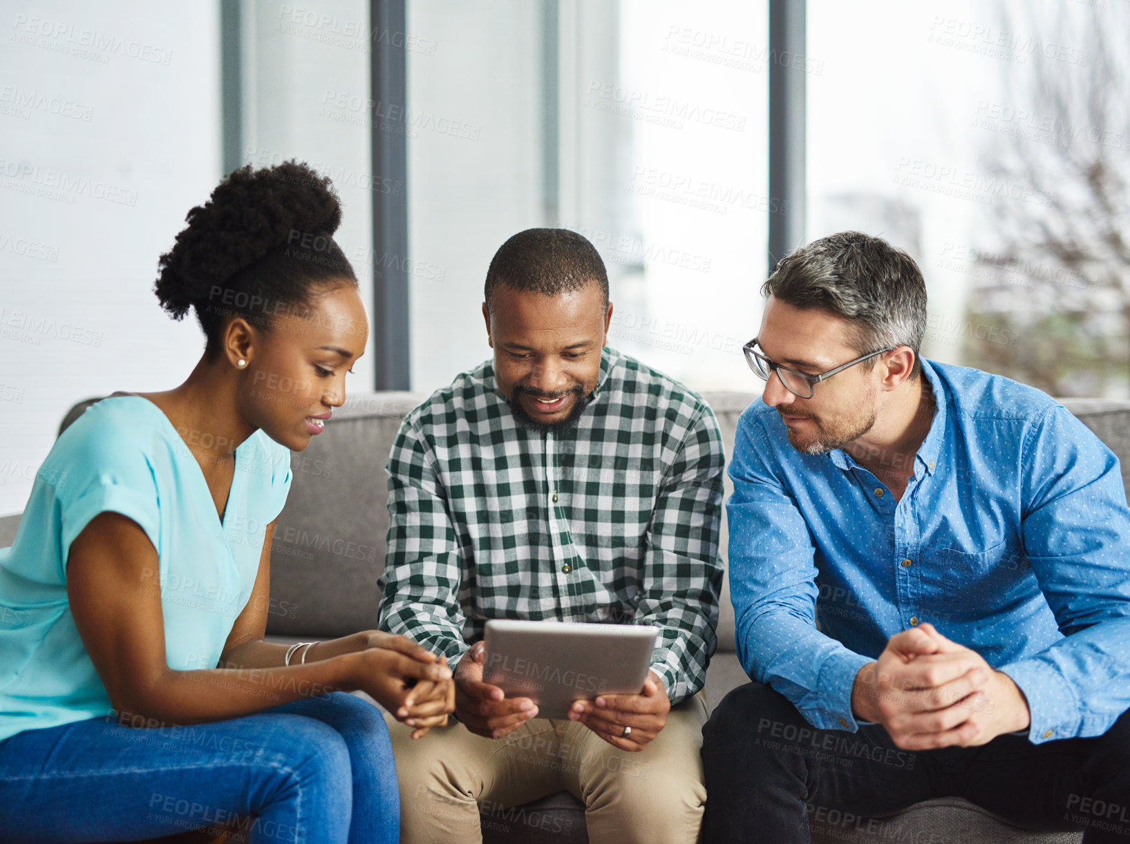 Buy stock photo Shot of a creative team discussing something on a digital tablet