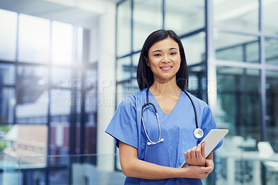 Buy stock photo Portrait of a young female doctor holding a digital tablet while standing in a hospital