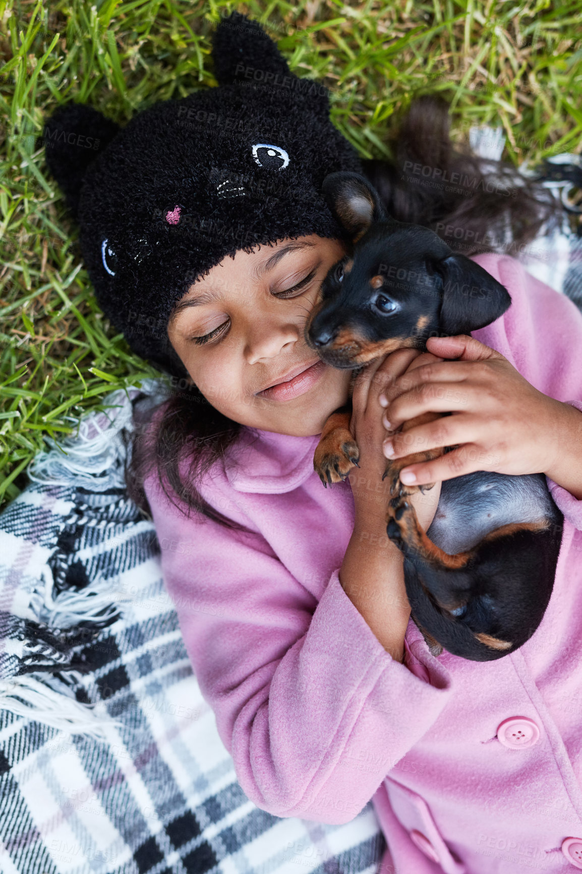 Buy stock photo Grass, girl and dog lying on blanket for bonding, caring and spend time together in park. Outdoor, puppy and child with happiness for relaxing, comfort and embrace love with smile or care in nature