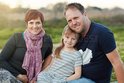 Buy stock photo Portrait of a cute little girl and her parents sitting outside together