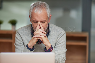 Buy stock photo Shot of a stressed out mature businessman using a laptop while working in an office