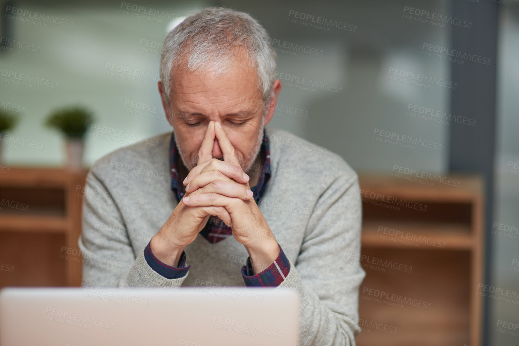 Buy stock photo Shot of a stressed out mature businessman using a laptop while working in an office