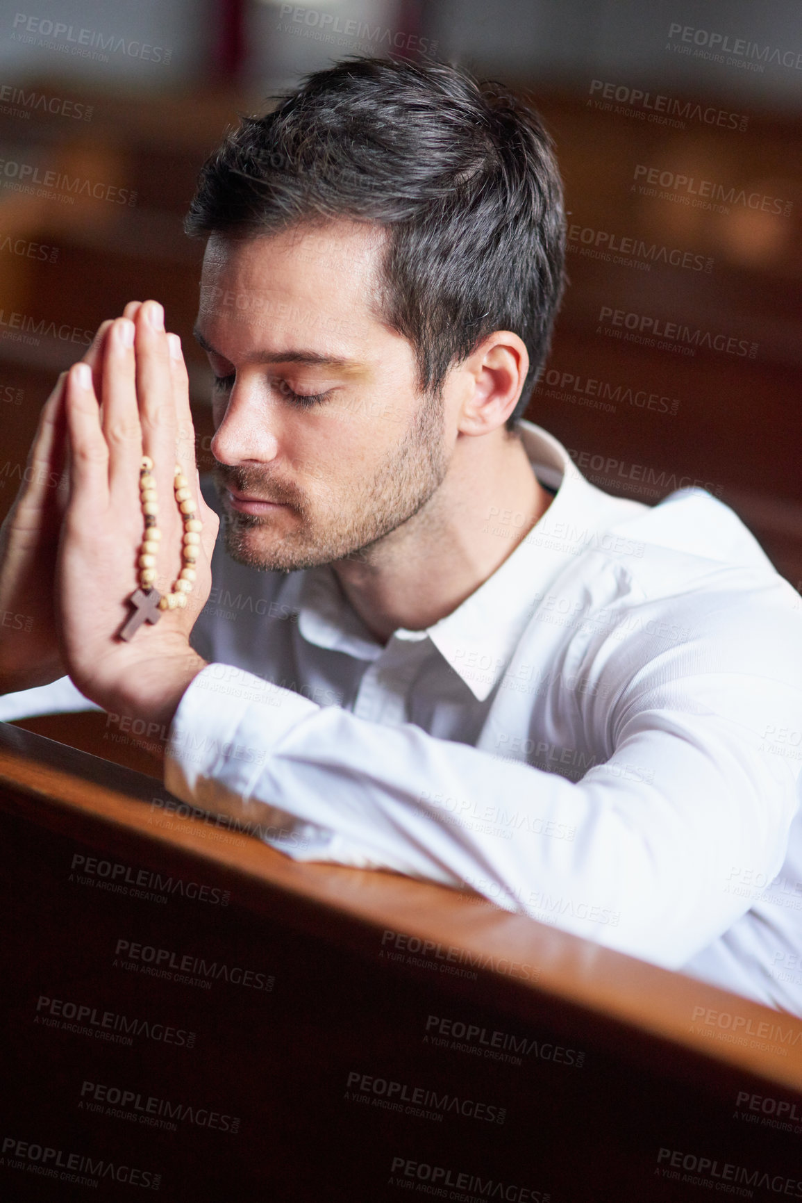 Buy stock photo Shot of a young man praying in a church