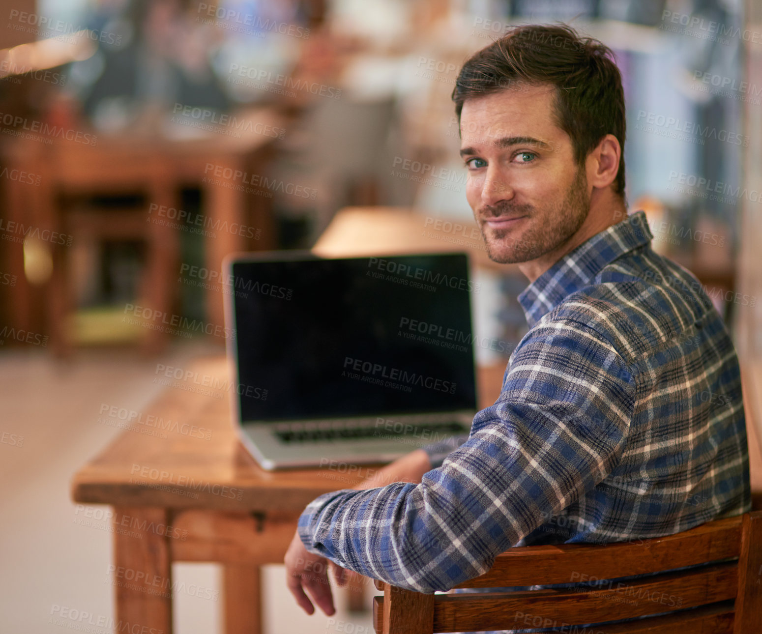 Buy stock photo Portrait of a young man using his laptop while sitting in a coffee shop