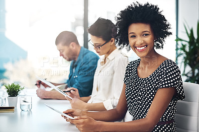 Buy stock photo Portrait of a smiling businesswoman sitting in a boardroom using a digital tablet with colleagues in  the background