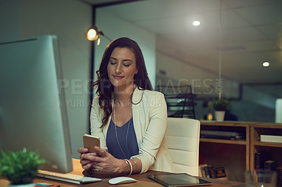 Buy stock photo Cropped shot of a young businesswoman using her cellphone while working late in an office