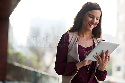 Buy stock photo Shot of a businesswoman using her tablet while standing outside