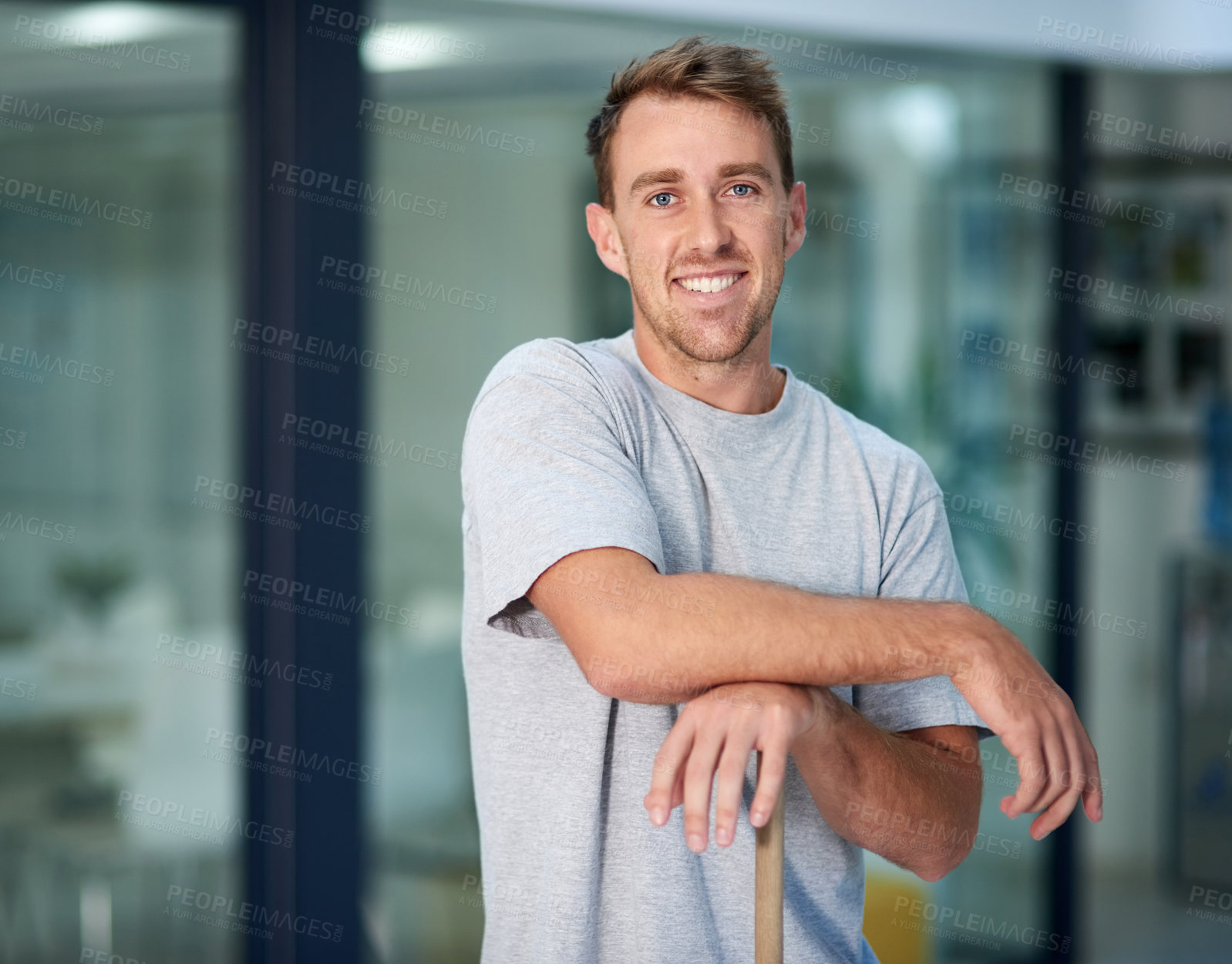 Buy stock photo Portrait of a young man leaning on a mop while cleaning the office floor