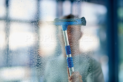 Buy stock photo Shot of a young man cleaning the windows in the office