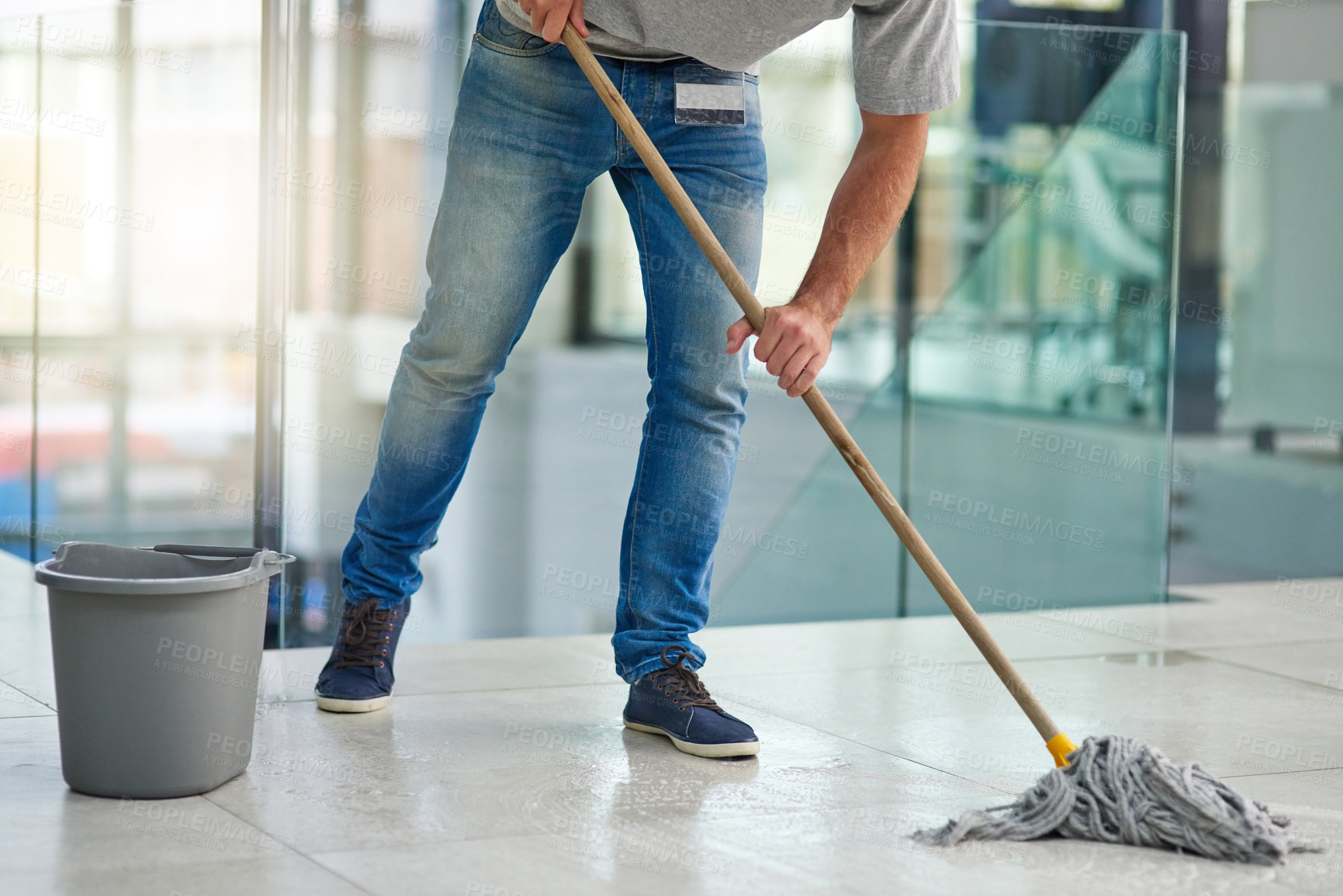 Buy stock photo Shot of an unrecognizable man mopping the office floor