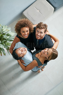 Buy stock photo High angle portrait of a group of  businesspeople standing arm in arm in a huddle in a modern office