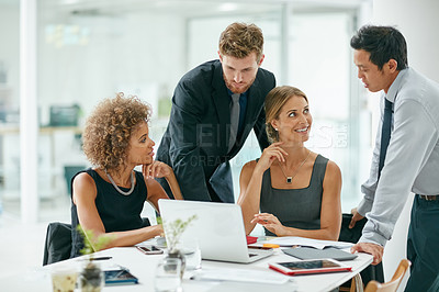 Buy stock photo Shot of a group of businesspeople working on a  laptop together in a modern office