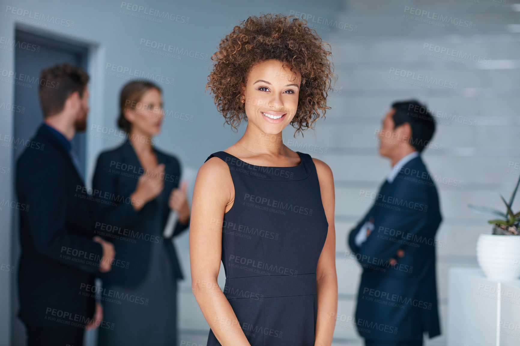 Buy stock photo Portrait of a young businesswoman standing in an office with colleagues in the background