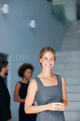 Buy stock photo Portrait of a young businesswoman standing in an office with colleagues in the background