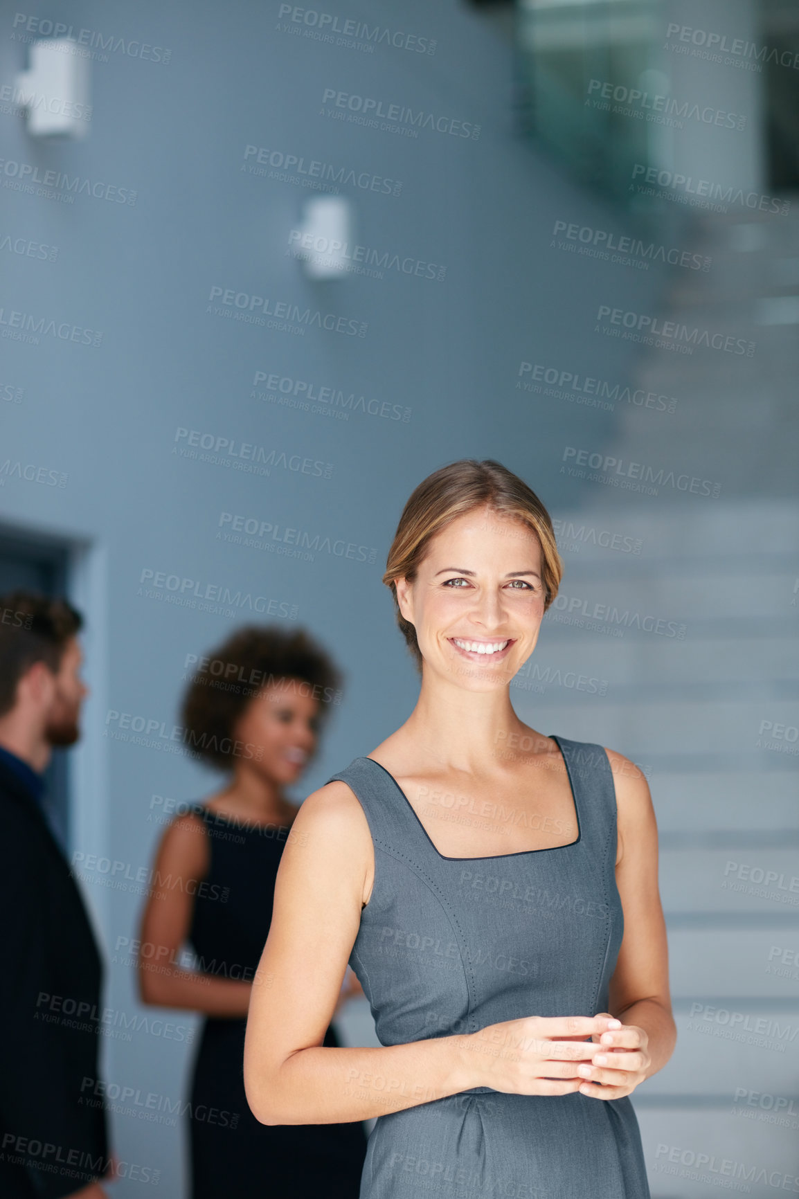 Buy stock photo Portrait of a young businesswoman standing in an office with colleagues in the background