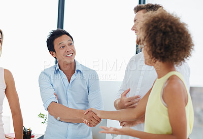 Buy stock photo Shot of a group of businesspeople congratulating their colleague on a promotion by shaking her hand