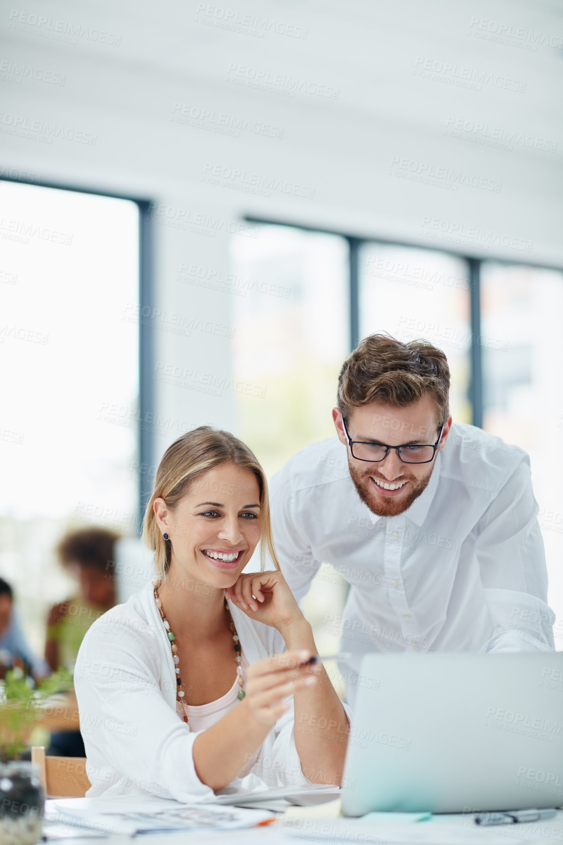 Buy stock photo Shot of a businesswoman and her male colleague working together on a laptop in their office