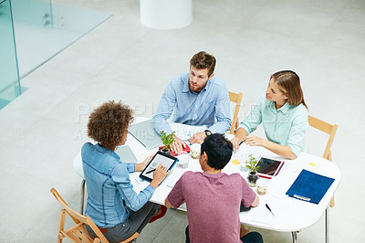 Buy stock photo High angle shot of a group of businesspeople talking together around a table in an office
