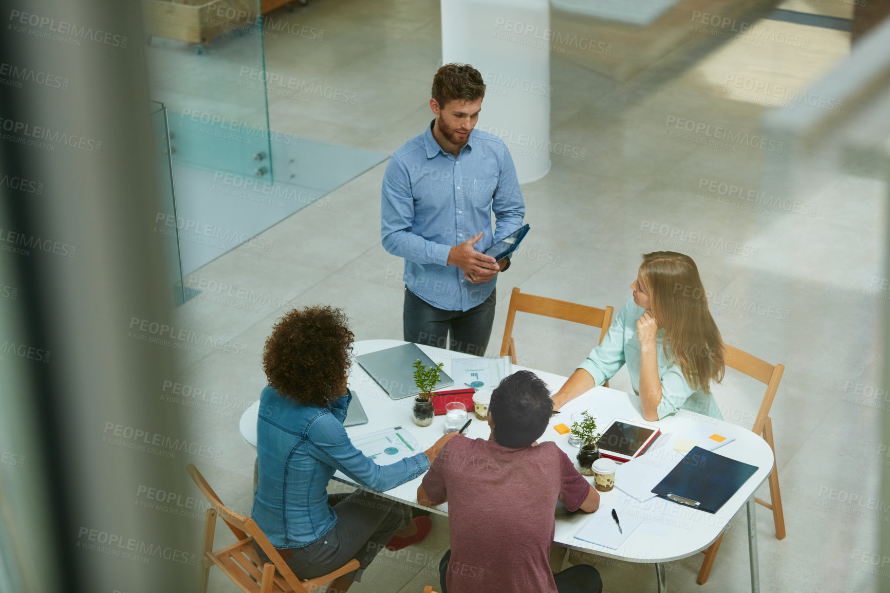 Buy stock photo High angle shot of a group of businesspeople talking together around a table in an office