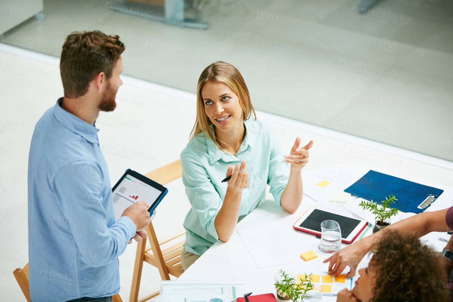 Buy stock photo High angle shot of a group of businesspeople talking together around a table in an office