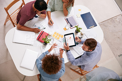 Buy stock photo High angle shot of a group of businesspeople working together around a table in an office
