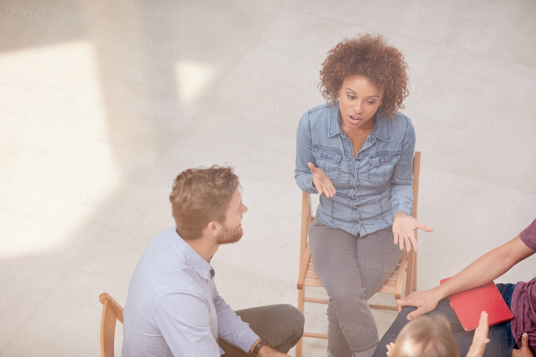 Buy stock photo High angle shot of a group of businesspeople talking together while sitting in a circle in an office