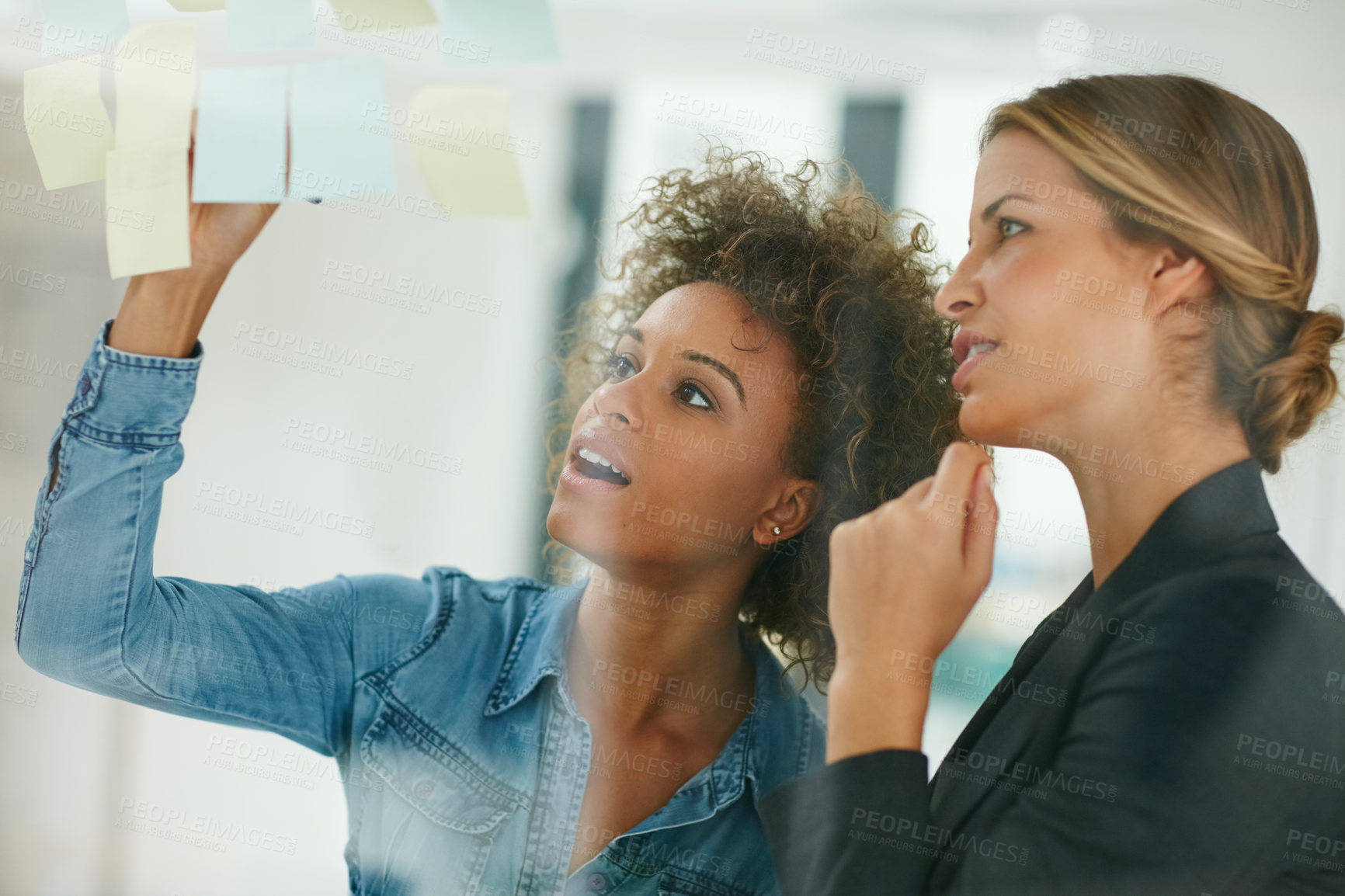 Buy stock photo Shot of coworkers using sticky notes against the wall during a brainstorming session