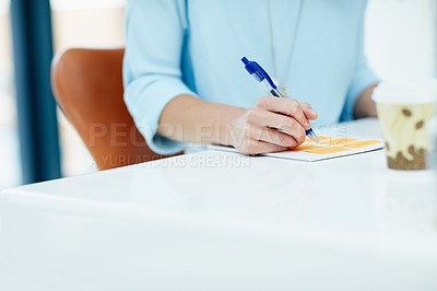 Buy stock photo Cropped shot of a young businesswoman writing notes in an office