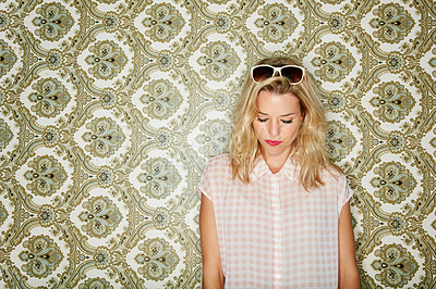 Buy stock photo Shot of a young woman posing against a wallpaper background