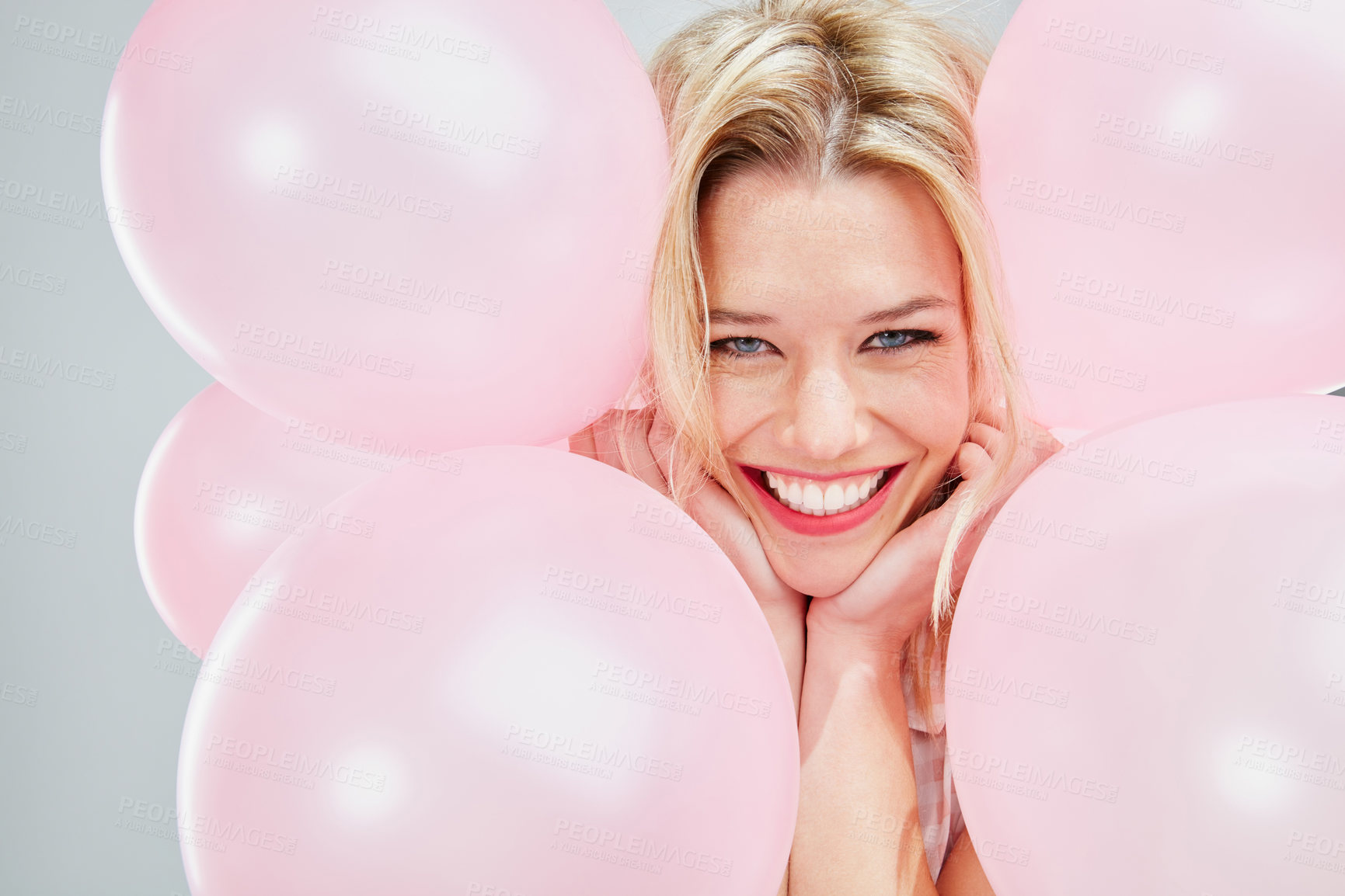 Buy stock photo Cropped shot of a beautiful young woman posing with pink balloons