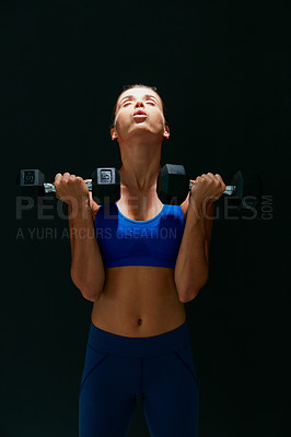 Buy stock photo Studio shot of a fit young woman working out with weights against a dark background