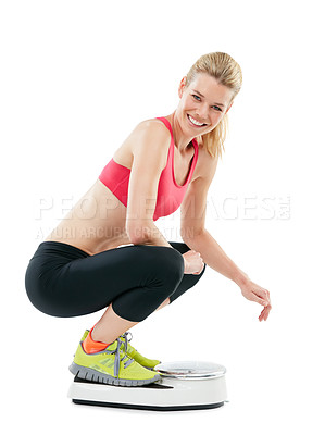 Buy stock photo Studio shot of a young woman weighing herself on a scale